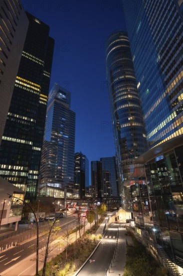 La defense financial district in paris at twilight, modern glass skyscrapers with illuminated offices reflecting blue hour light, conveying finance, business and urban growth