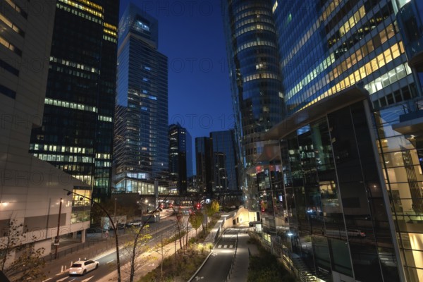 La defense skyline at blue hour, modern glass skyscrapers and illuminated streets reflecting city lights, bustling financial district with contemporary urban energy