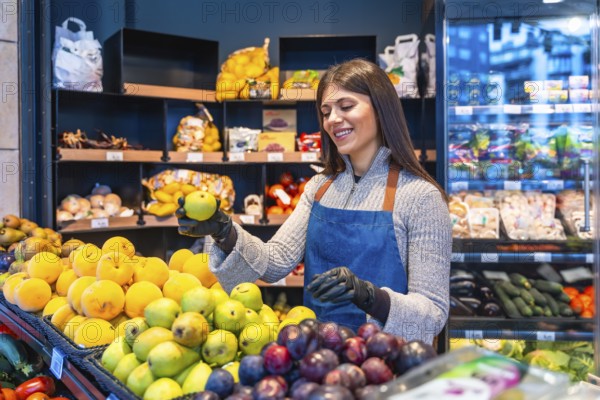 Smiling female greengrocer wearing an apron and gloves, carefully arranging fresh fruit on a display shelf in a bustling supermarket, ensuring quality and presentation for customers
