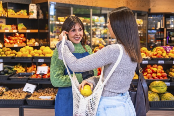 Friendly supermarket employee smiling and assisting a customer holding a reusable net bag to put fresh organic fruit in, promoting sustainable shopping and good service in a grocery store