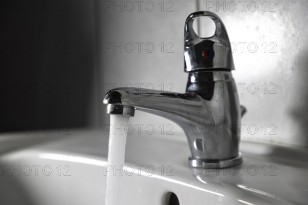 Chrome plated faucet with running water in the bathroom