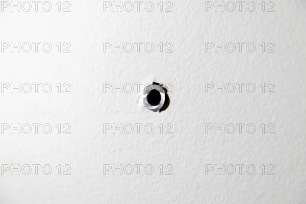Single drill hole with dowel in a white wall