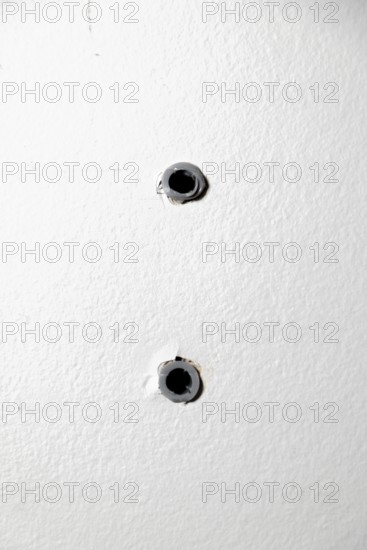 Two drill holes with dowels in a white wall