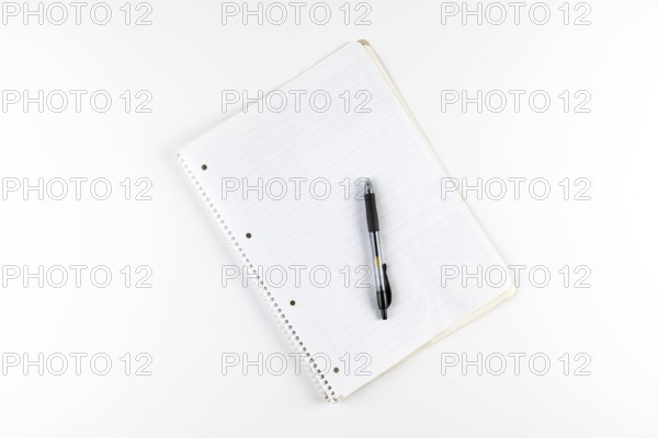 Notebook with checkered pages and a black ballpoint pen on a white background