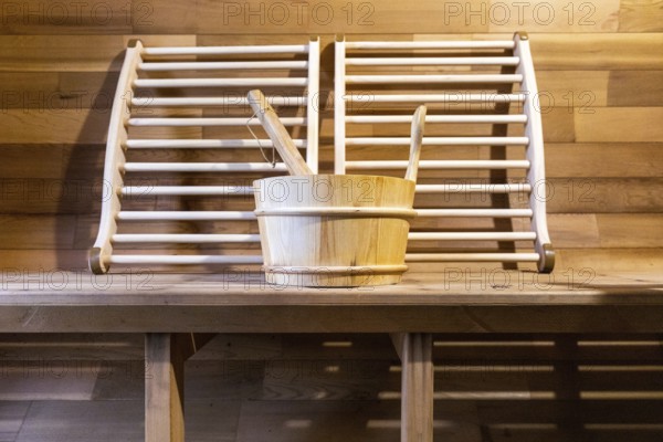 Steam and hot stone wooden cedar compact sauna interior with heating stone electrical device, hot water bucket and benches