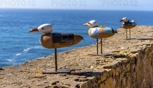Wooden seagulls, art on the fortress at Farol de Nazare lighthouse, an annual meeting place in autumn to watch the big waves on the North Beach, Nazaré, Portugal