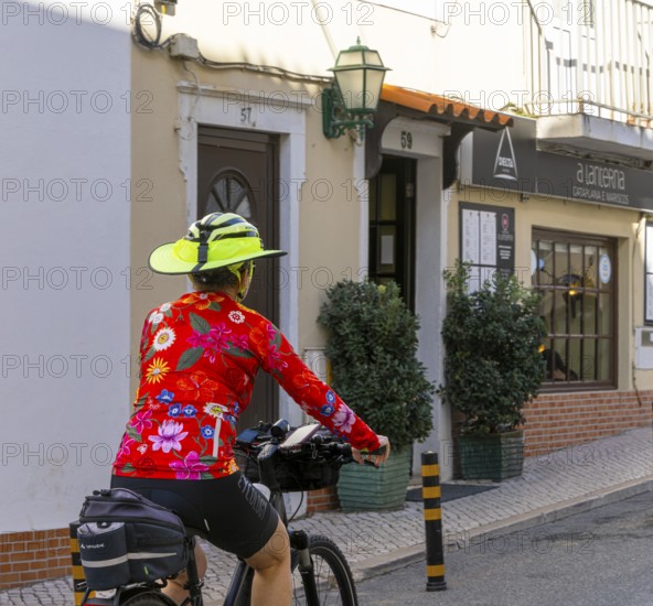Female cyclist wearing yellow sunshade on bicycle helmet, Nazare, Portugal