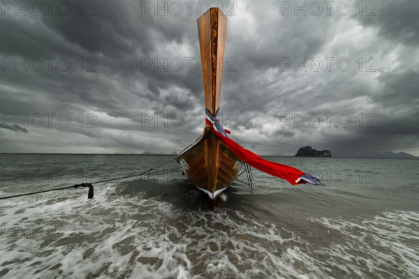 Longtail boat on the beach with dark rain clouds behind it, Koh Ngai island, Andaman Sea, Satun province, southern Thailand, Thailand