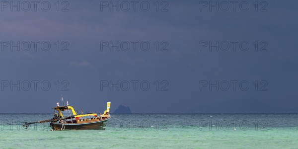 Longtail boat (Thai: Ruea Hang Yao) on the beach, behind it an approaching thunderstorm, Koh Ngai Island, Andaman Sea, Satun Province, Southern Thailand, Thailand