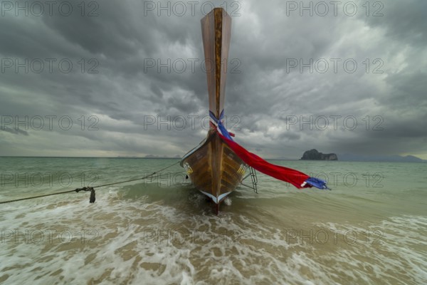Longtail boat on the beach with dark rain clouds behind it, Koh Ngai island, Andaman Sea, Satun province, southern Thailand, Thailand