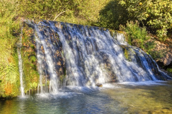Fascinating waterfall flowing over green moss rocks into a natural basin, El Kelaa wild stream in Morocco