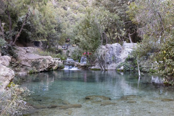 Clear pond surrounded by green vegetation with small waterfalls and rocks, El Kelaa river in Morocco
