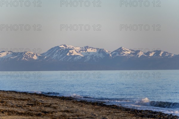 Anchor Point beach on Cook Inlet in the evening light, snowy mountain peaks of the Kenai Peninsula, Anchor River State Recreation Area, Alaska, USA