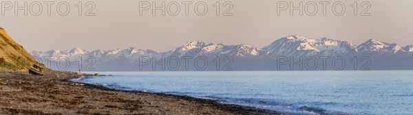Boat on Anchor Point beach on Cook Inlet in the evening light, snowy mountain peaks of the Kenai Peninsula, Anchor River State Recreation Area, Alaska, USA