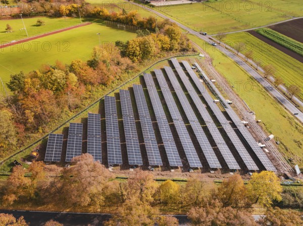 Solar systems next to a sports field, surrounded by autumn-colored trees, Bau PV Freifaechenanlage, Weil der Stadt, Germany