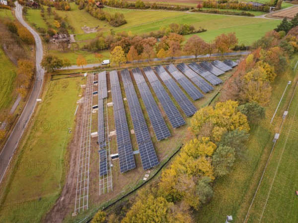 Collection of solar panels surrounded by trees in autumn colors, Bau PV Freifaechenanlage, Weil der Stadt, Germany