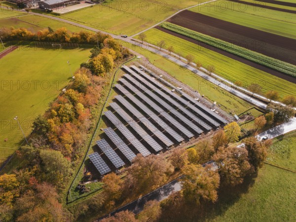 Aerial view of solar panels surrounded by autumn trees and green fields, Bau PV Freifaechenanlage, Weil der Stadt, Germany