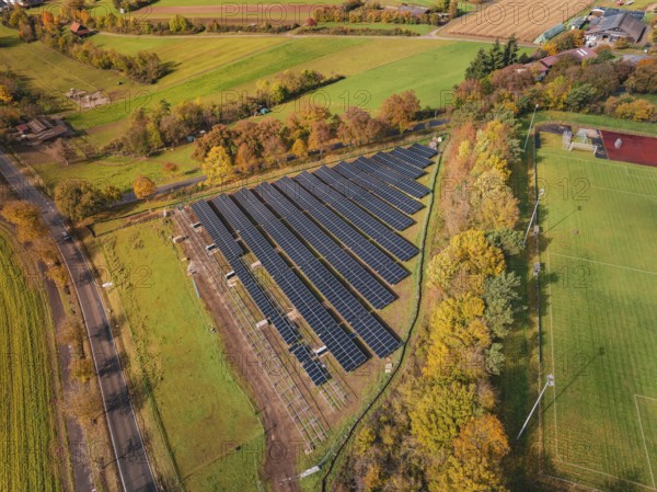 Aerial view of a solar field in an autumn landscape with fields and colorful trees, PV Freifaechenanlage construction, Weil der Stadt, Germany
