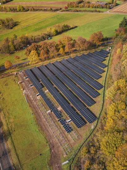 Panoramic aerial view of a solar plant surrounded by green fields and autumn trees, PV open-air plant construction, Weil der Stadt, Germany