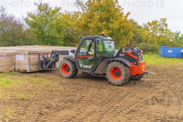 A forklift truck transports boxes across muddy soil in an autumn environment, Bau PV Freifaechenanlage, Weil der Stadt, Germany