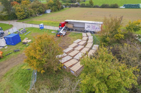 A forklift truck moves boxes next to a truck in a green autumn landscape, Bau PV Freifaechenanlage, Weil der Stadt, Germany