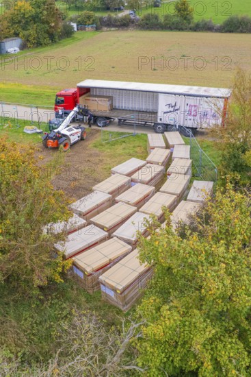 Aerial view of a forklift truck working next to a truck with boxes and autumn trees, PV Freifaechenanlage construction, Weil der Stadt, Germany
