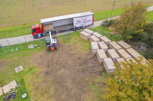 A forklift unloads boxes from a truck on a rural road, Bau PV Freifaechenanlage, Weil der Stadt, Germany