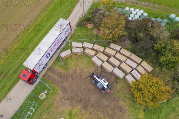 Aerial view of a forklift and truck in a colorful autumn landscape with boxes, construction PV Freifaechenanlage, Weil der Stadt, Germany