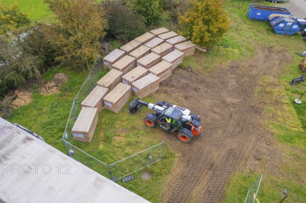 Aerial view of boxes and a forklift truck on a fenced grassy area with containers, PV Freifaechenanlage construction, Weil der Stadt, Germany