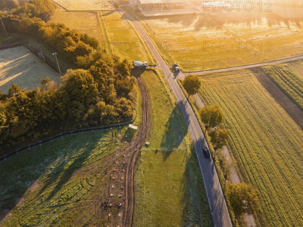 Morning light over a vast landscape with trees and an asphalted road, Bau PV Freifaechenanlage, Weil der Stadt, Germany