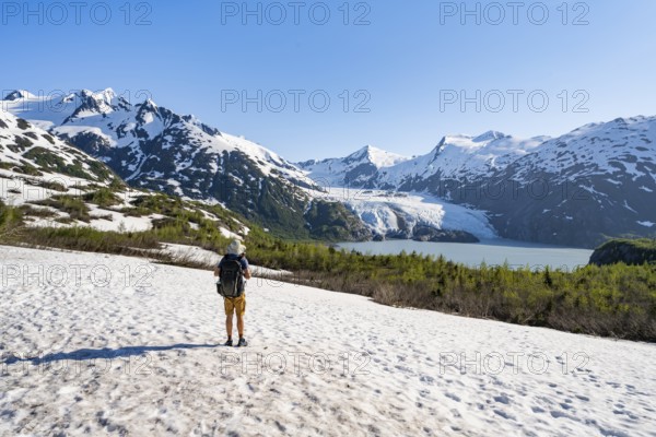 Hikers on a snowfield on the Portage Pass Trail, snowy mountains, Portage Glacier and Portage Lake, near Whittier, Alaska, USA