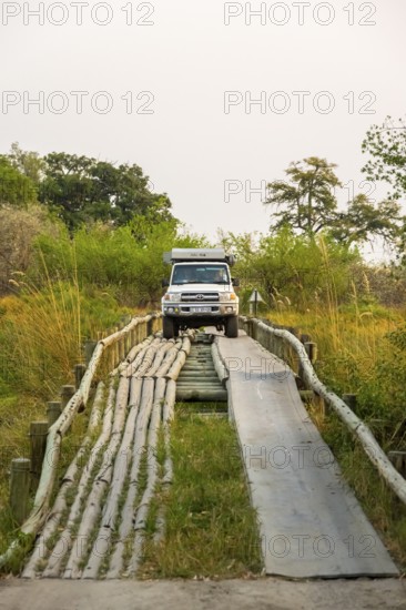 Car drives over Third Bridge, bridge over swamp in Moremi Game Reserve, Botswana
