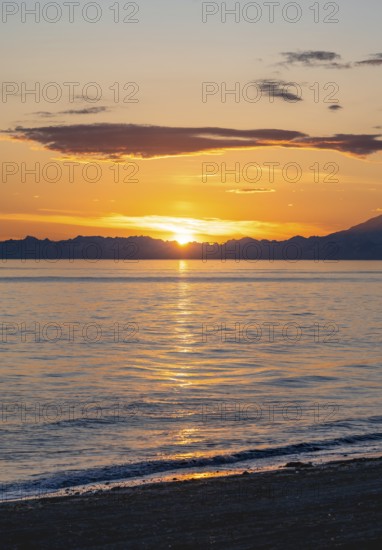 View of Cook Inlet at sunset, picturesque golden light of the midnight sun, mountains of the Aleutian Range, Anchor Point, Anchor River State Recreation Area, Alaska, USA