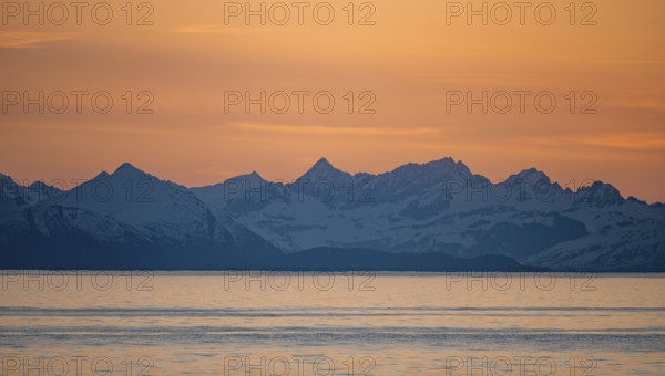 View of Cook Inlet on white mountain peaks of the Aleutian Range, picturesque golden light of the midnight sun, Anchor Point, Anchor River State Recreation Area, Alaska, USA