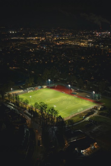 Illuminated soccer field in an urban area at night with glowing city lights, Sindelfingen, BÃ¶blingen district, Germany
