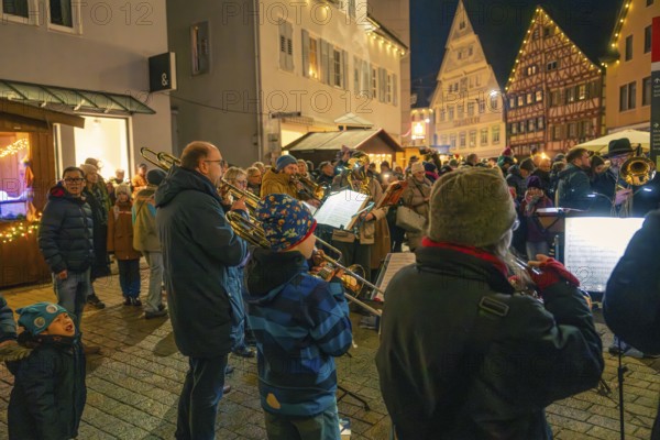 A brass band plays on a busy street surrounded by bright decorations, Christmas market 2025, Nagold, Black Forest, Calw district, Germany