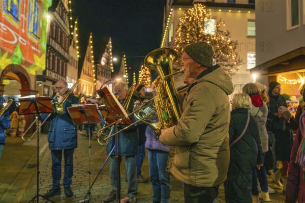 A brass band plays at night in front of Christmass-illuminated buildings, Christmas market 2025, Nagold, Black Forest, Calw district, Germany