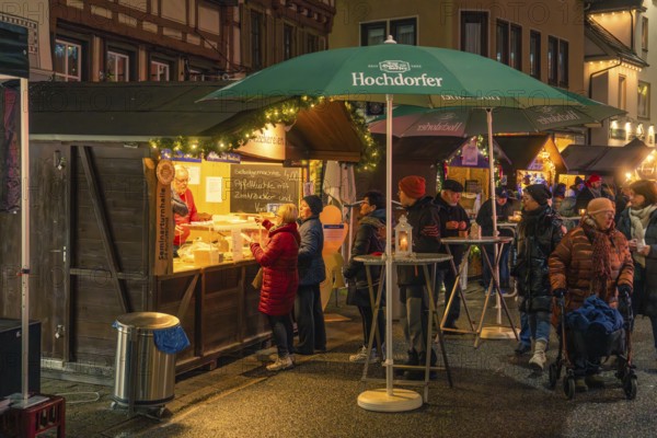 Residents and visitors gather around a food stand with festive lights, Christmas market 2025, Nagold, Black Forest, Calw district, Germany