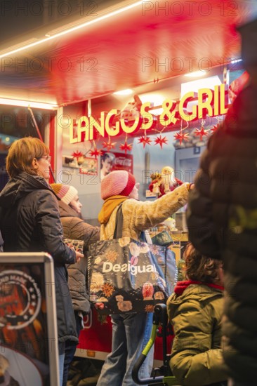 People stand at a red-lit food stand at a Christmas market, Christmas market 2025, Nagold, Black Forest, Calw district, Germany