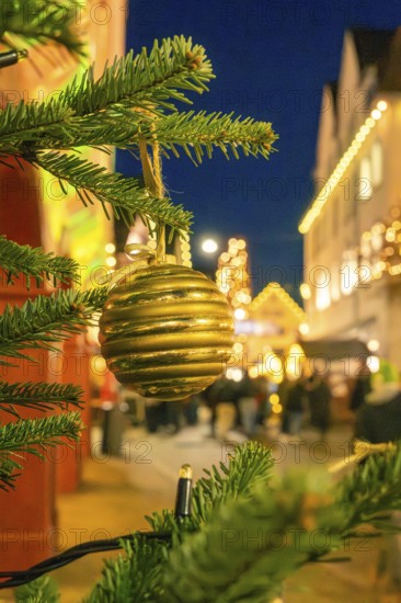 Golden Christmas ball on a pine branch in a festively lit area, Christmas market 2025, Nagold, Black Forest, Calw district, Germany