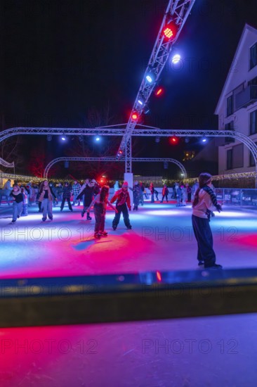 Colourful lights on an ice rink at night, people skating and friendly togetherness, Christmas market 2025, Nagold, Black Forest, Calw district, Germany