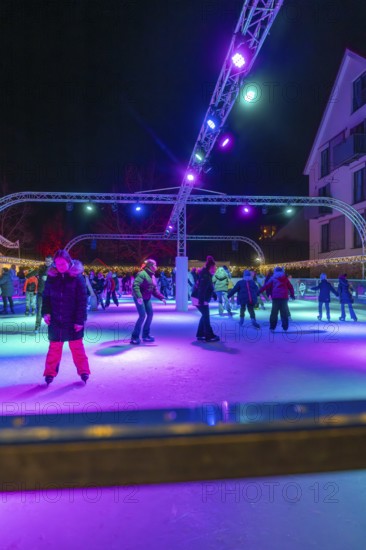 Night view of an ice rink with colorful lights, many people skating, Christmas market 2025, Nagold, Black Forest, Calw district, Germany