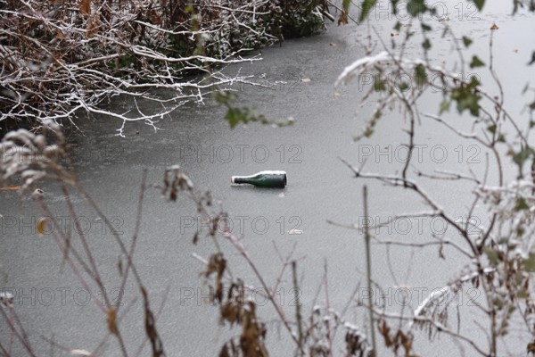 Symbolic picture of garbage in nature, bottle on frozen lake, winter, Germany