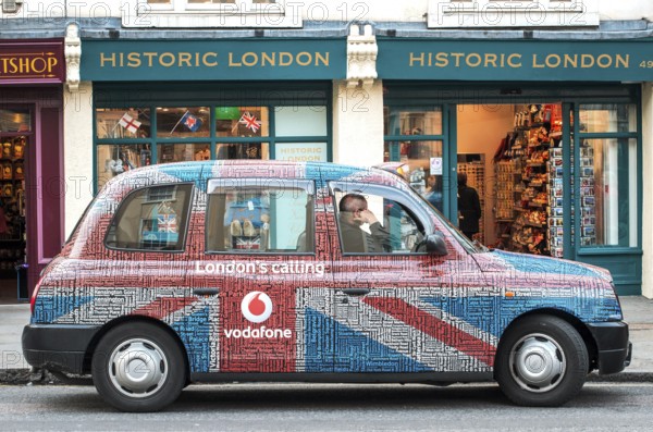 A London taxi with a special taxi advertisement from the London's calling advertising campaign by Vodafone in the design of Union Jack, London England, Great Britain