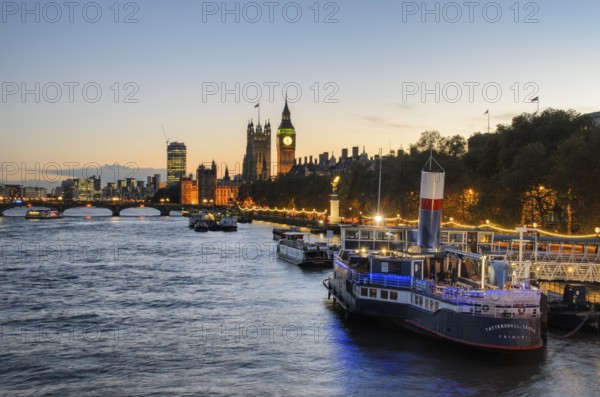View over the Thames at golden hour with the Palace of Westminster and Elizabeth Tower, Big Ben, a moored ship in front of it, converted into a floating bar and restaurant PS Tattershall Castle, London, England, Great Britain