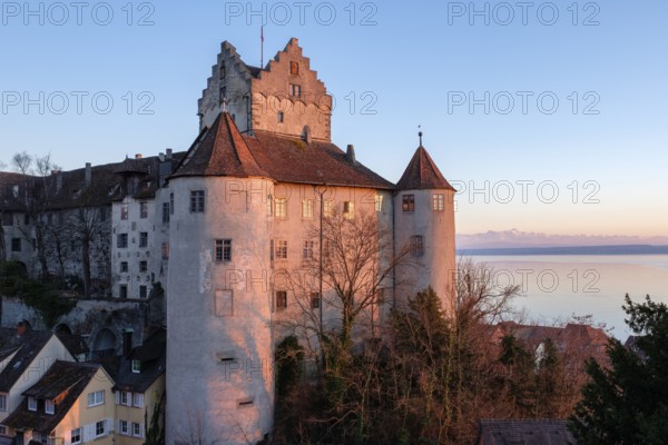 The historic Meersburg Castle, illuminated by the setting sun, right behind it Lake Constance with the Swiss Alps on the horizon, Lake Constance District, Baden-WÃ¼rttemberg, Germany
