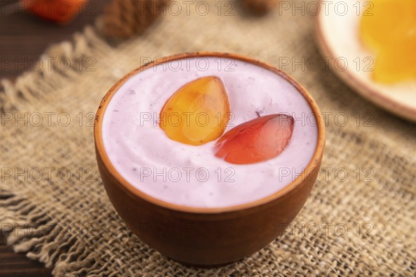 Purple Yogurt, with jelly candy on brown wooden background and linen textile, side view, close up, minimalism, selective focus