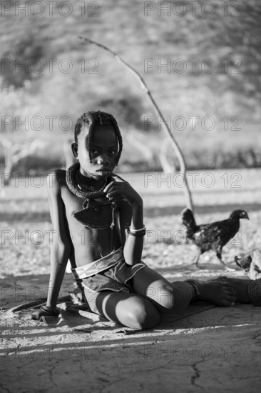 Black and white, Himba child, by the fire in the morning light, traditional Himba village, Kaokoveld, Kunene, Namibia