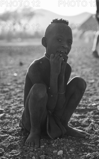 Himba child sitting on ground, traditional Himba village, Kaokoveld, Kunene, Namibia