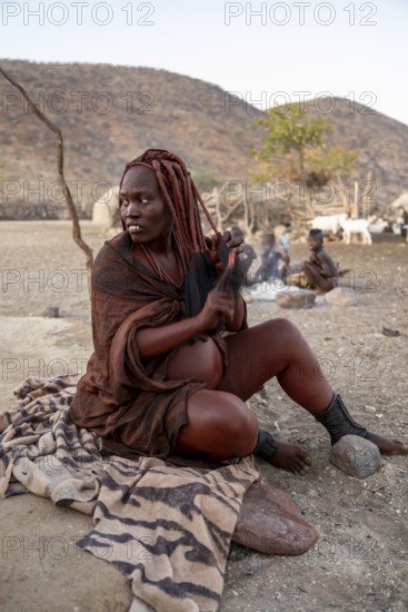Married Himba woman sitting in front of the hut in the morning, traditional Himba village, Kaokoveld, Kunene, Namibia